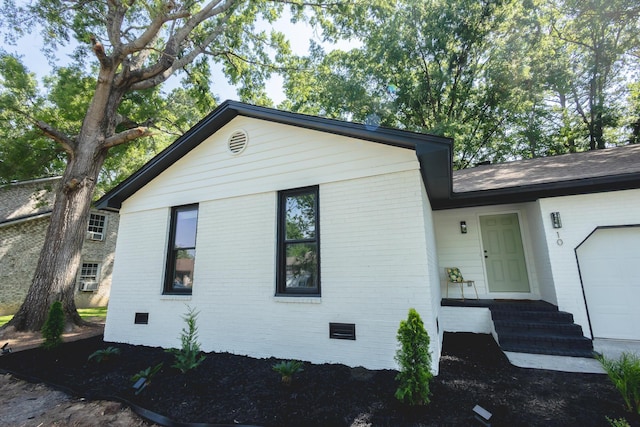 view of property exterior with brick siding, crawl space, and a garage