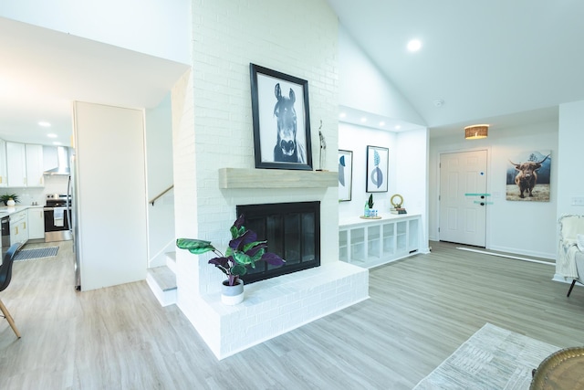 living area with stairway, light wood-style floors, recessed lighting, a brick fireplace, and high vaulted ceiling