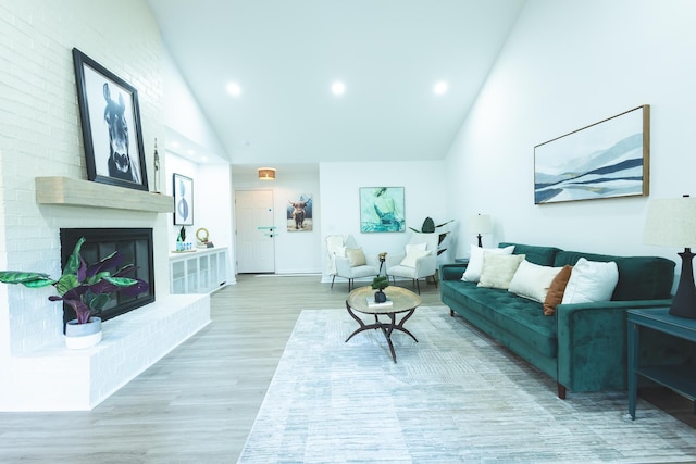 living area with high vaulted ceiling, wood finished floors, recessed lighting, and a fireplace