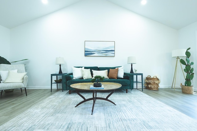 living area featuring lofted ceiling, wood finished floors, and baseboards