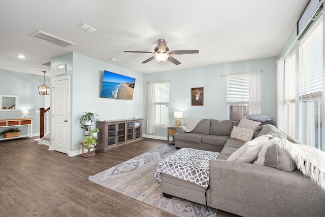 living room featuring dark wood-type flooring, a wealth of natural light, and ceiling fan with notable chandelier