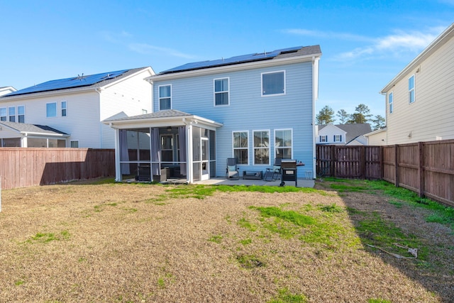 back of property with a patio area, a yard, a sunroom, and solar panels