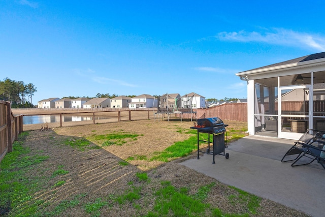 view of yard featuring a sunroom, a trampoline, a water view, and a patio