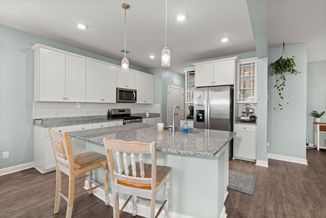 kitchen featuring white cabinetry, a center island with sink, appliances with stainless steel finishes, tasteful backsplash, and sink