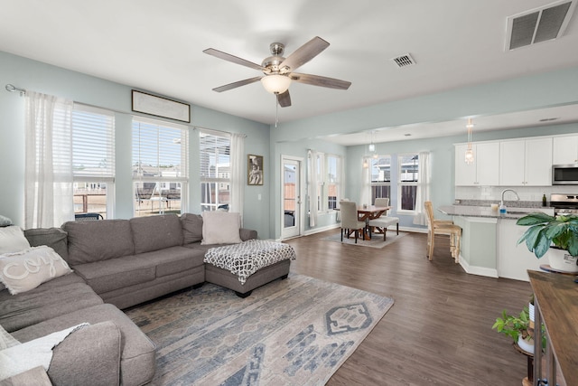 living room with dark wood-type flooring, ceiling fan, and sink