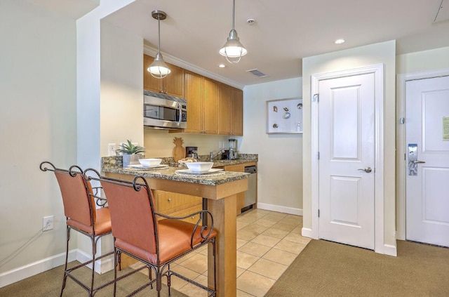 5802 Palmetto Dr Unit B 314, Isle Of Palms, SC 29451 - kitchen with stainless steel microwave, a breakfast bar, brown cabinets, pendant lighting, and a peninsula