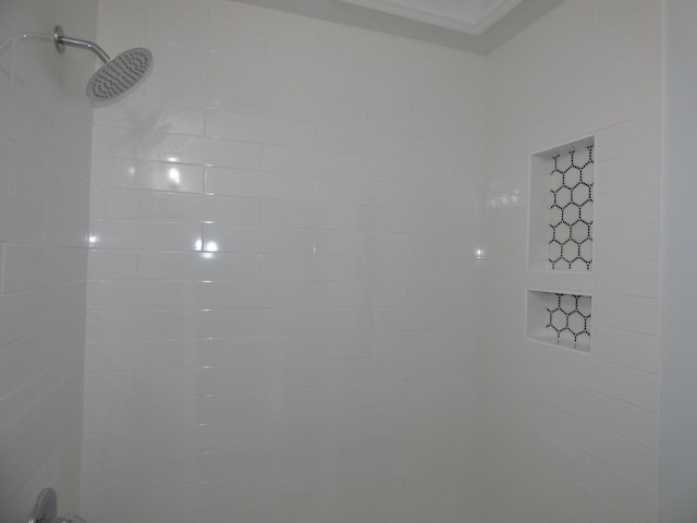 interior details featuring a tile shower and ornamental molding