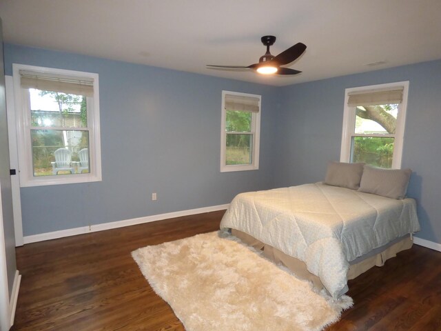 bedroom with multiple windows, ceiling fan, and dark hardwood / wood-style flooring