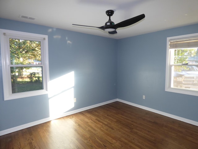 empty room with dark hardwood / wood-style floors, ceiling fan, and a wealth of natural light