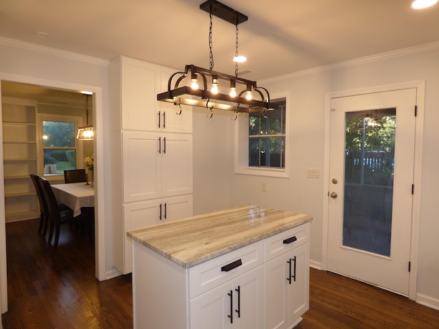 kitchen with light stone counters, crown molding, decorative light fixtures, white cabinets, and dark hardwood / wood-style floors