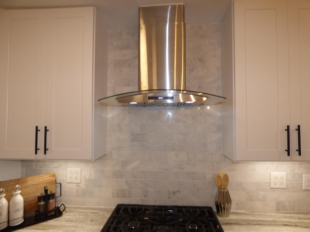 room details featuring white cabinets, wall chimney exhaust hood, and decorative backsplash