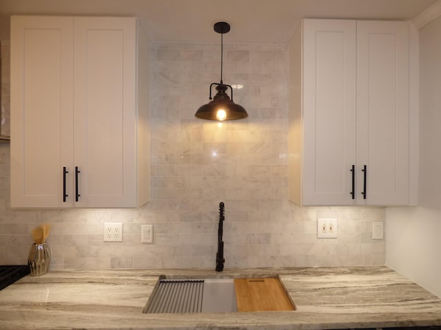 details with light stone countertops, white cabinetry, hanging light fixtures, and tasteful backsplash