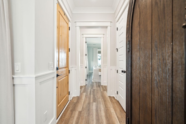 corridor featuring ornamental molding and light hardwood / wood-style flooring