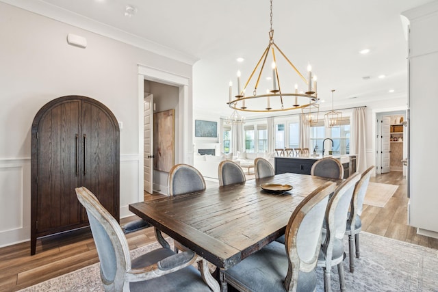 dining room with ornamental molding, sink, and light wood-type flooring