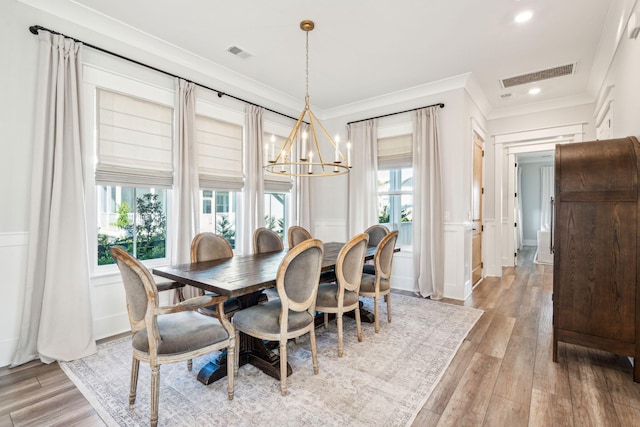 dining space with crown molding, a notable chandelier, and light wood-type flooring