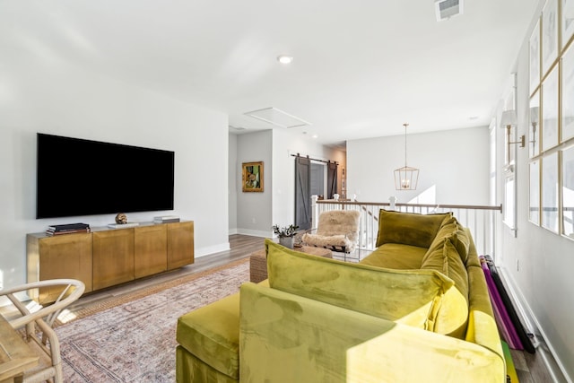 living room with light hardwood / wood-style floors, a notable chandelier, and a barn door