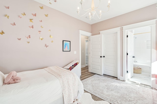 bedroom featuring a notable chandelier, hardwood / wood-style floors, and ensuite bathroom