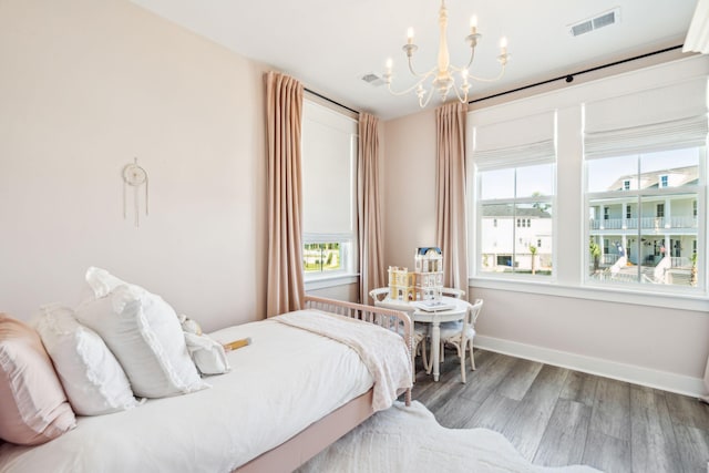 bedroom with wood-type flooring and an inviting chandelier