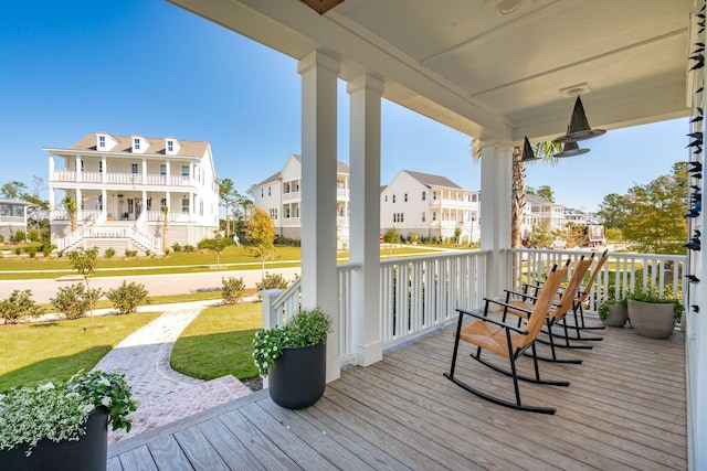 wooden terrace featuring covered porch and a lawn