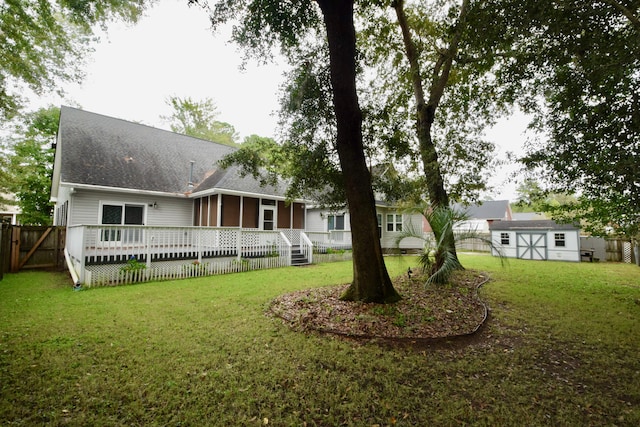 rear view of property featuring a storage unit, a yard, a sunroom, and a wooden deck