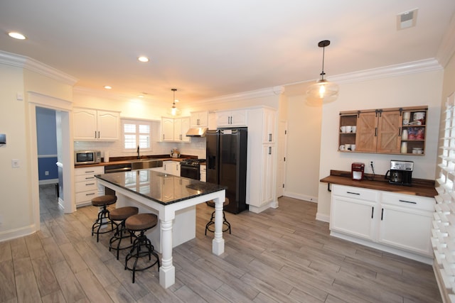 kitchen featuring a kitchen island, black refrigerator with ice dispenser, white cabinetry, and pendant lighting