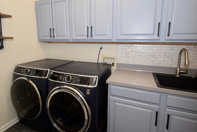 laundry area featuring sink, washer and clothes dryer, and cabinets