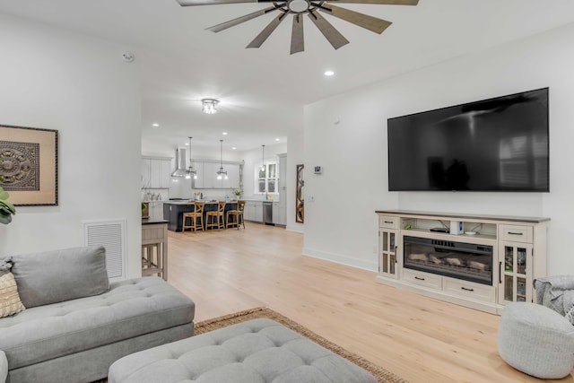 living room featuring light hardwood / wood-style floors and ceiling fan