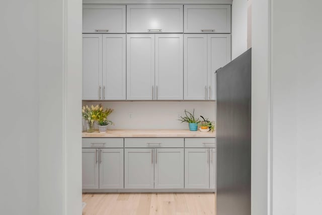 kitchen with stainless steel refrigerator, gray cabinets, and light hardwood / wood-style flooring