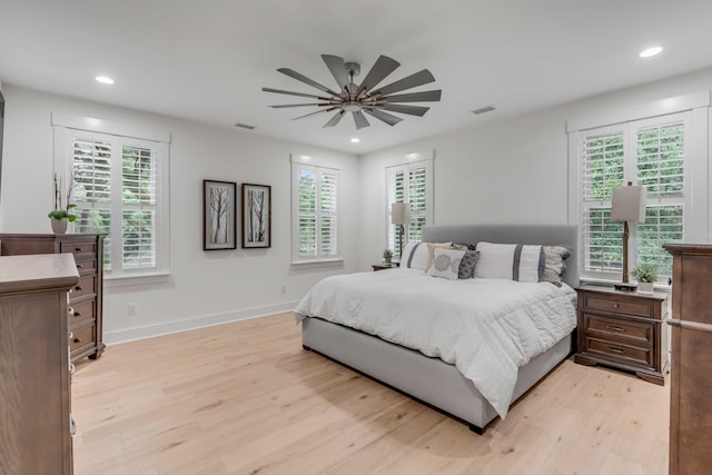 bedroom featuring ceiling fan, multiple windows, and light wood-type flooring