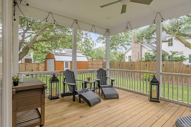 wooden terrace with a yard, ceiling fan, and a storage unit