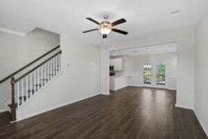 unfurnished living room featuring baseboards, stairs, a ceiling fan, and wood finished floors