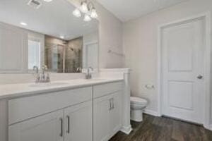 bathroom featuring double vanity, wood finished floors, a sink, and toilet