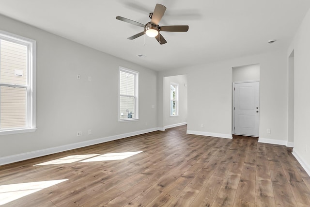 unfurnished living room featuring wood finished floors, baseboards, and ceiling fan