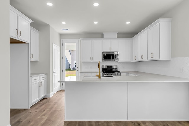 kitchen featuring light countertops, decorative backsplash, white cabinetry, and stainless steel appliances