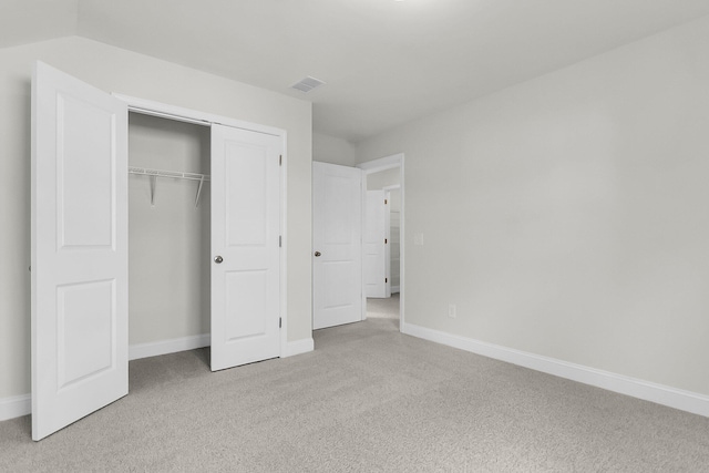 unfurnished bedroom featuring light carpet, a closet, visible vents, and baseboards