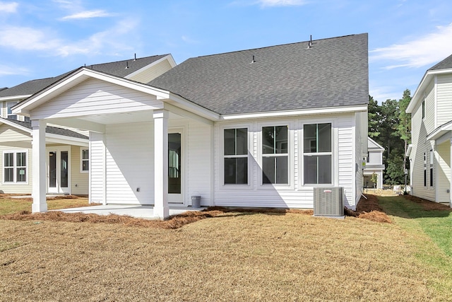rear view of house with a lawn, roof with shingles, and cooling unit