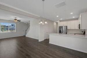 kitchen featuring light countertops, dark wood-type flooring, white cabinets, a peninsula, and stainless steel fridge with ice dispenser