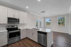 kitchen with a peninsula, ornamental molding, stainless steel appliances, and light countertops