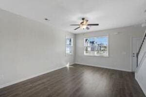 unfurnished living room featuring ceiling fan, stairs, baseboards, and dark wood finished floors