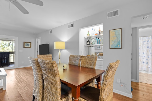 dining area with light wood finished floors, baseboards, and visible vents