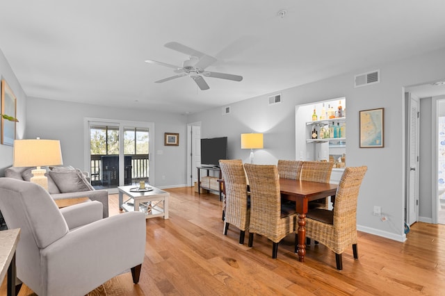 dining space with light wood-style flooring, visible vents, ceiling fan, and baseboards