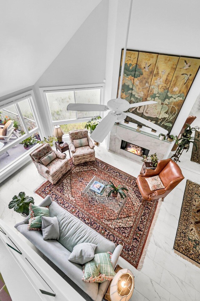 living room featuring a high end fireplace, lofted ceiling, and ceiling fan