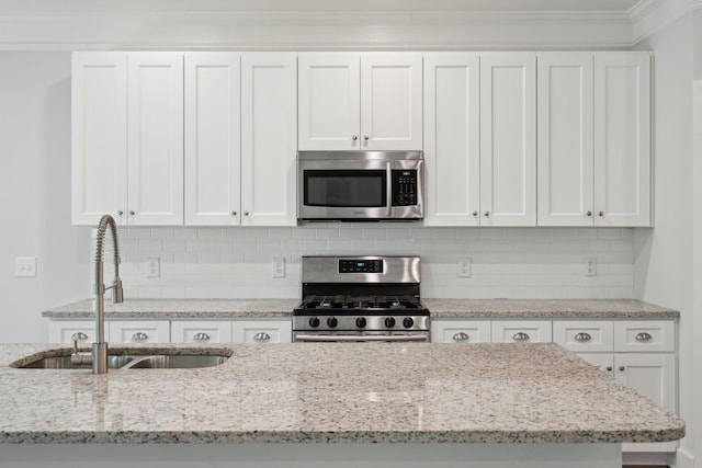 kitchen featuring light stone counters, sink, stainless steel appliances, and white cabinets