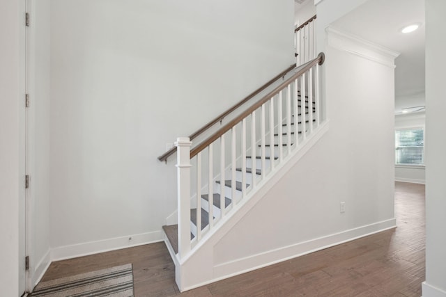 staircase with wood-type flooring and crown molding