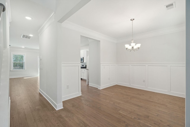 unfurnished dining area featuring hardwood / wood-style flooring, crown molding, and a chandelier