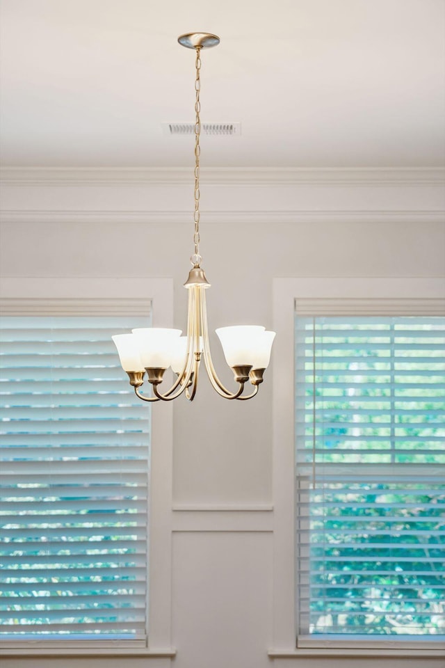 interior details featuring ornamental molding and a chandelier