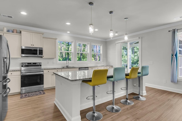 404 Bowstring Dr, Huger, SC 29450 - kitchen featuring appliances with stainless steel finishes, light wood finished floors, healthy amount of natural light, ornamental molding, and a kitchen island
