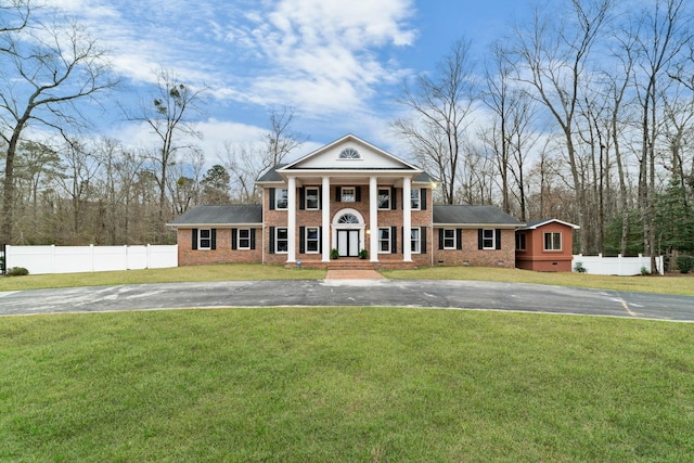 neoclassical home featuring crawl space, aphalt driveway, a front yard, and fence