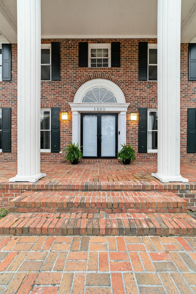 view of exterior entry featuring brick siding and french doors