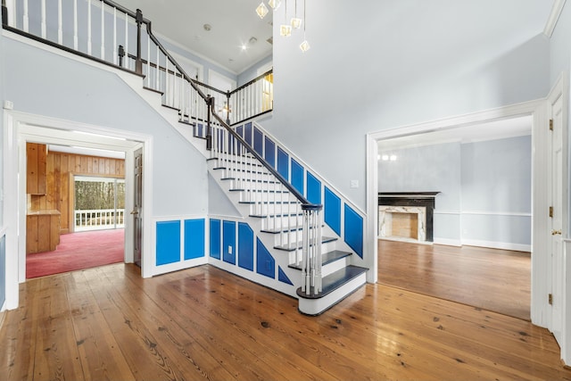 1560 NW Lee Blvd, Orangeburg, SC 29118 - stairway featuring a high ceiling, hardwood / wood-style floors, a fireplace, and crown molding